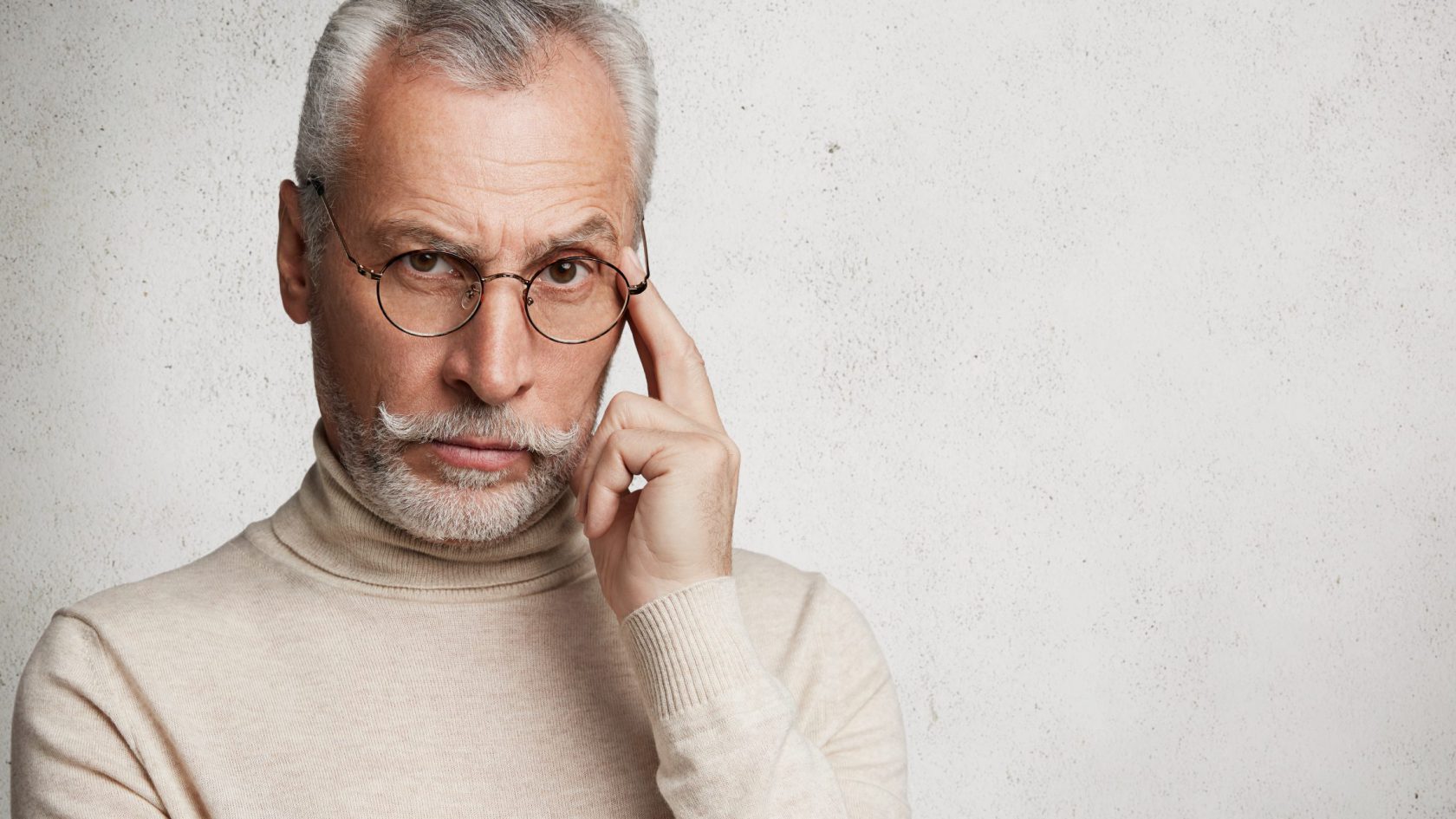 Horizontal shot of thoughtful pensive elderly bearded male keeps finger on temple, contemplates about something important, isolated over blank copy space for your advertising content or text
